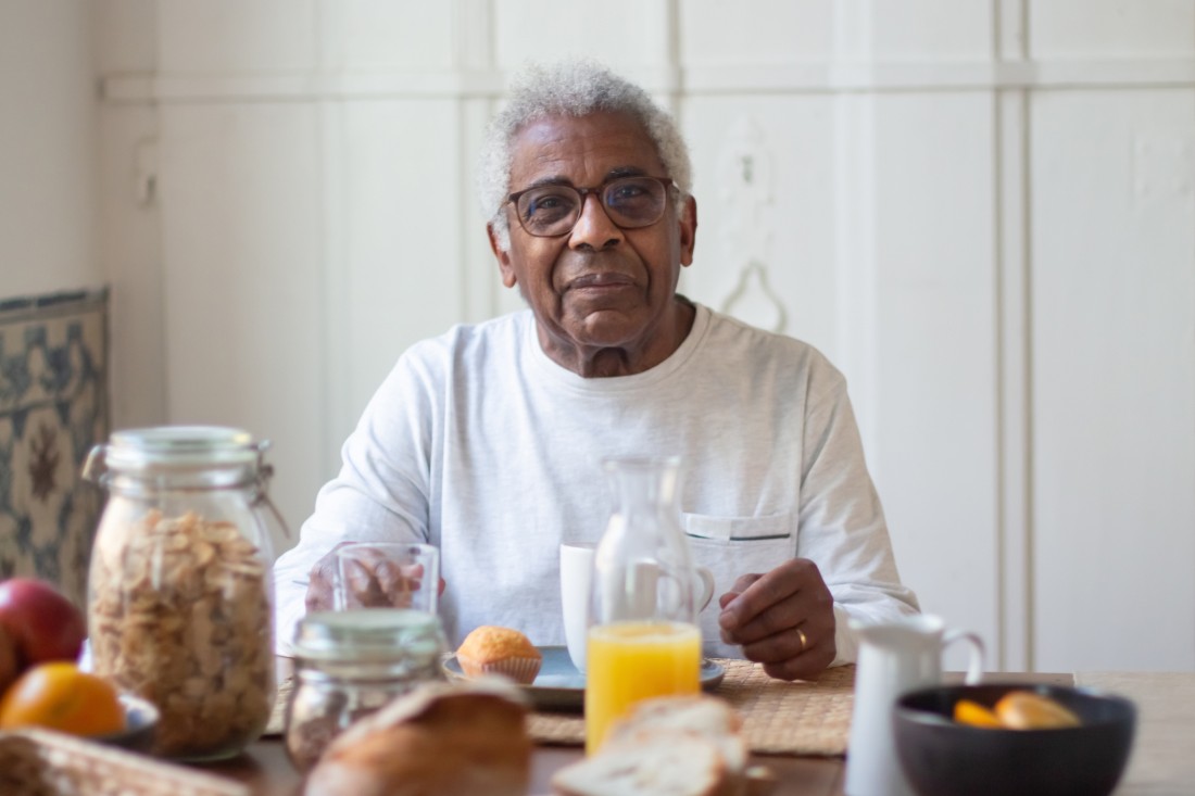 An older man sits at the breakfast table